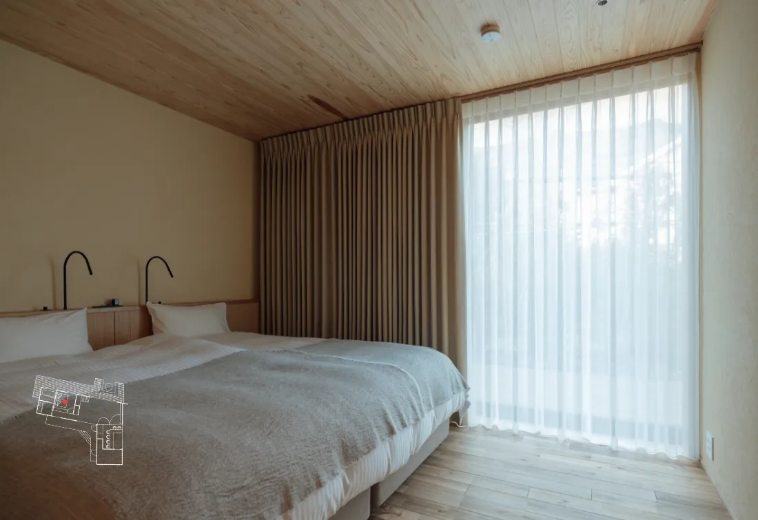 The bedroom on the first floor is a simple Western-style room. The bed throw is by Watanabe Textile.